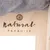 Natural Paradise Logo auf hellem Holz mit Pfotenmotiv und grauem Stoff oben sichtbar.