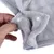 Close-up of grey fabric material with press studs, shown by a hand. Demonstration of the product's fastening option.