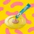 Dreamies Creamy treat being squeezed from a tube onto a yellow plate, showing the product’s creamy texture.