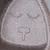 Nahaufnahme einer grauen Oberfläche mit eingraviertem Symbol: zwei geschlossene Augen und eine Nase in Form eines T. Symbol möglicherweise dekorativ oder funktional.
