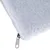 Gros plan sur un coin de coussin blanc en tissu polaire avec fermeture éclair métallique visible.