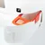 Compartiment orange avec filtre rectangulaire visible dans une litière pour chat blanche, bouton noir avec symbole flèche et levier blanc marqué OPEN.