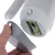 Dispensador blanco con asa y compartimento para rollo de bolsas verdes para excrementos de perro. Tapa gris extraíble a mano.