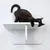 Gatto nero sdraiato su un supporto da parete bianco a due livelli. Il prodotto è utilizzato come mobile o superficie per gatti.