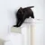Gatto nero su tiragraffi bianco con rullo in sisal e superficie imbottita per sdraiarsi.