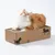 Katzenliege aus Pappe mit Kratzfläche, dekoriert mit schwarzen Katzenmotiven. Orange-weisse Katze liegt darauf.