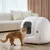 PETKIT automatická toaleta pro kočky v bílé barvě, s kočkou před ní. Moderní design, vhodná do interiéru. Viditelné ovládací prvky a otvor pro snadný přístup.