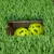 Green plastic grass mat with cut-out, two yellow plastic play balls visible underneath.