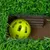 Yellow plastic ball in an area covered with artificial grass, surrounded by cardboard walls.