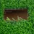 Close-up of a rectangular section in green artificial turf with visible brown cardboard underneath.