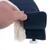 Gros plan sur une main tenant un accessoire en tissu bleu avec intérieur en fausse fourrure beige, étiquette visible : L, Nomad Soft, Faux Fur, LA 565009.