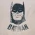 Logo di Batman con la scritta 'BATMAN' su sfondo beige.