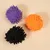 Tre palline da gioco soffici nei colori viola, arancione e nero su sfondo beige.