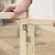Montage eines Holzrahmens mit Scharnieren und Plexiglas. Hände halten die Teile zusammen, Schrauben sind sichtbar.