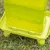 Green plastic container with raised base, suitable for outdoor use on grass.