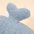 Detailansicht eines hellblauen, flauschigen Stoffteils mit einer abstehenden Form, Material wirkt weich und plüschig.