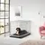 Metall-Hundebox mit offener Tür, graues Kissen im Inneren, platziert in einem modernen Wohnzimmer mit rosa Sessel und Lampe.