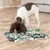 Hund benutzt eine grüne und graue Schnüffelmatte auf dem Boden. Hund benutzt eine grüne und graue Schnüffelmatte auf dem Boden.