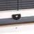 Close-up of a black fastener on a wooden frame with metal grid.