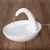 Fontaine à eau blanche en plastique avec bec courbé, jet d’eau continu dans un bol rond, posée sur un sol en bois. Câble d’alimentation visible à droite.