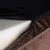 Husă cu fermoar deschis, arătând strat de spumă albă și material textil maro cu model. Fermoarul este negru, iar partea superioară a husei pare din material sintetic.
