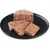 Close-up of sliced wet food on a black plate, showing the texture and composition of the food.