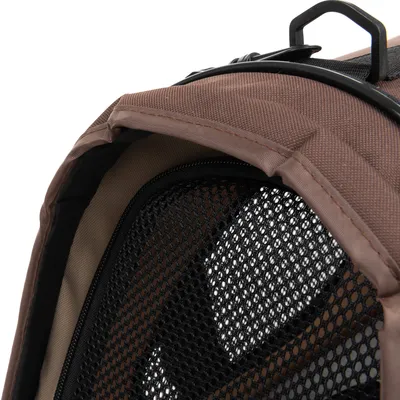 Détail d’un sac de transport marron pour animaux avec maille noire et fermeture éclair visible, poignée en plastique sur le dessus.