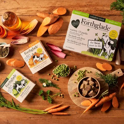 Forthglade puppy food variety pack with visible ingredients including sweet potato, peas, carrots and herbs. Packaging highlights grain free, complete meal, 75% lamb or chicken.