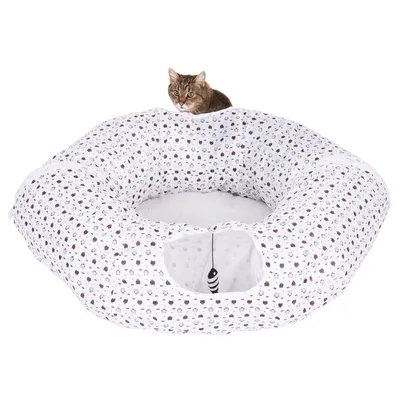 Rundes Katzenbett mit weissem Stoff und Katzenmuster, integriertem Spielzeugfisch und Öffnung. Katze sitzt oben auf dem Bett.