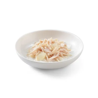 Ciotola bianca con alimento umido per animali, composto da strisce di carne chiara in gelatina o brodo. Nessun marchio o testo visibile.