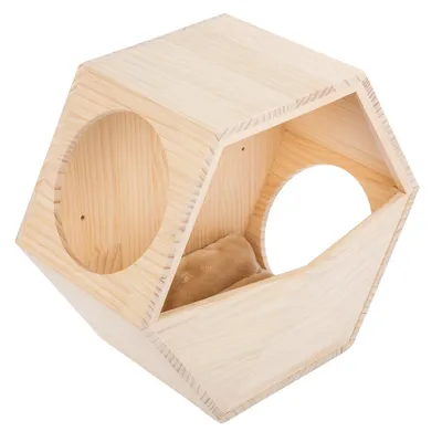 Casa de madera hexagonal con dos aberturas redondas y un cojín beige suave en el interior. Hecha de madera natural clara.