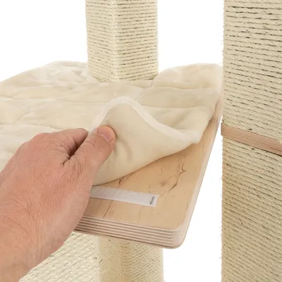 Mano levantando una funda acolchada beige de una plataforma de madera, parte de un rascador para gatos con postes de sisal visibles.