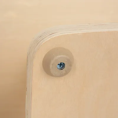 Detailaufnahme einer Holzplatte mit abgerundeter Ecke und sichtbarer Schraube in einer Kunststoffhalterung.