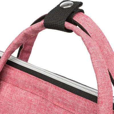 Detaljvy av en rosa väska med dragkedja och svart tryckknapp på bärhandtagen.