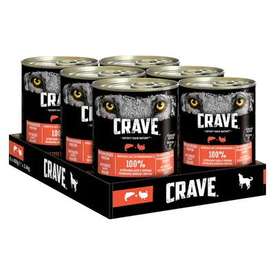 Crave wet dog food, 6 x 400g cans in tray. Visible text: Crave, Satisfy Their Nature, 100% natürlichem Lachs & Truthahn. Wolf eyes graphic on label. Dog and meat icons on packaging.
