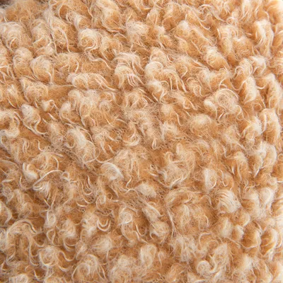 Nahaufnahme von beigem, flauschigem Material mit lockiger Struktur. Sichtbar sind die Textur und Fasern des Materials.