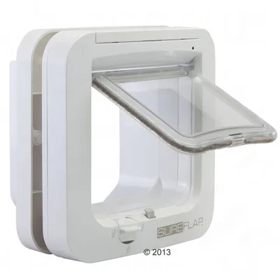 Puerta para mascotas SureFlap blanca de plástico con solapa transparente abatible y cierre giratorio visible en la parte inferior. Marca SureFlap impresa en el frontal.