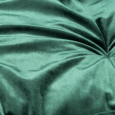Close-up van een groene, fluweelachtige stof met zachte textuur en plooivorming.