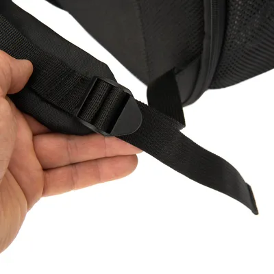 Close-up van een zwarte verstelbare riem met kunststof gesp, vastgehouden door een hand. Detailweergave van de bevestiging voor een product.