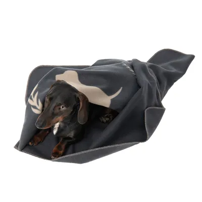 Pas leži na tamnosivoj deki s bež motivom psa i rogovlja, vidljiva tkanina s obrubljenim rubovima.