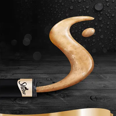 Crema per gatti Sheba spremuta da una bustina nera e oro, disposta a forma di S su fondo scuro in legno con gocce d'acqua. Marchio Sheba visibile sulla confezione.