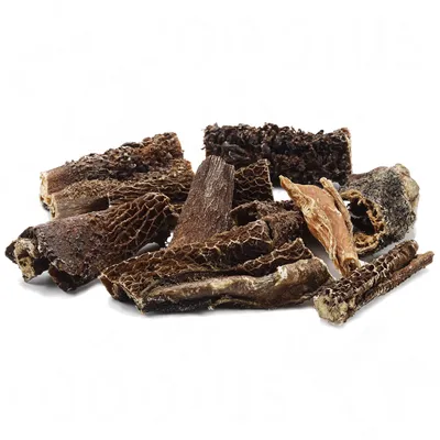 Morceaux de friandises séchées pour chien, texture rugueuse et couleur brun foncé, présentés en tas sur fond blanc. Aucun emballage ou marque visible.