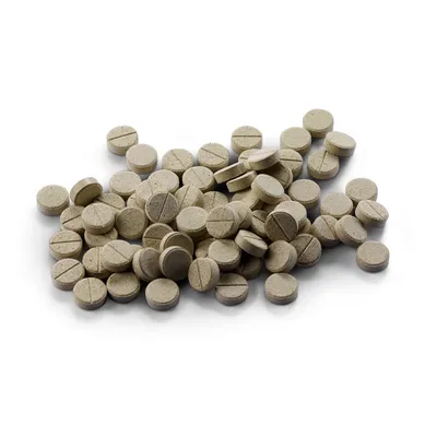 Braune Tabletten mit Bruchrille, lose gestapelt auf weissem Hintergrund.