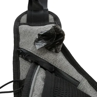 Detailaufnahme einer grauen Tasche mit integriertem Spender für schwarze Hundekotbeutel. Sichtbarer Reissverschluss und Netzmaterial.