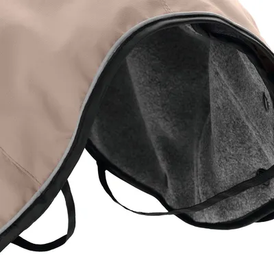 Widok szczegółowy beżowego koca dla psa z szarym polarowym wnętrzem i czarnymi paskami mocującymi.