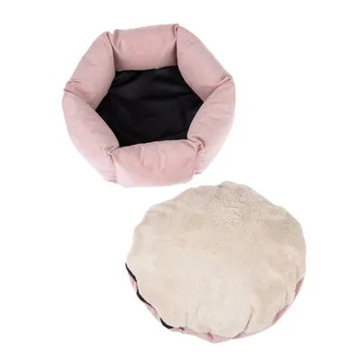 Rund lyserød kæledyrsseng med bløde kanter og sort bund, aftagelig beige pude i plys synlig ved siden af sengen. Materialer: stof og plys.