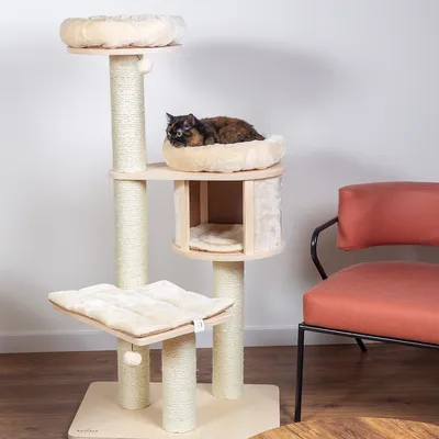Klösträd i trä och sisal med flera liggplatser, klösstolpar och en katt som vilar på en av plattformarna. Synlig beige färg och mjuka dynor.