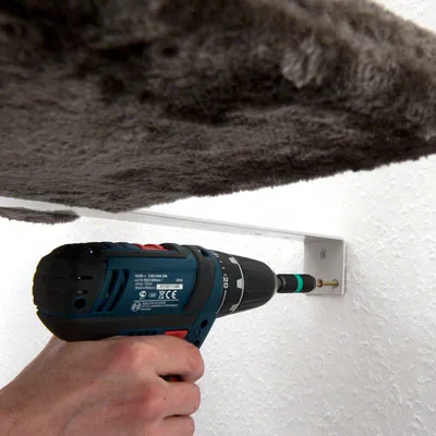 Montage eines Wandhalters mit Bohrmaschine und Schraube. Halterung dient zur Befestigung eines Kratzbaums an der Wand.