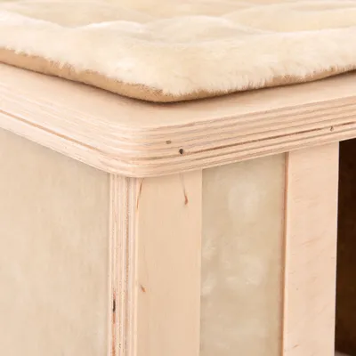 Estructura de madera con cojín beige y suave en la parte superior. Vista detallada de un mueble o accesorio.