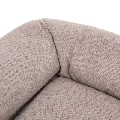Gros plan sur un coin de coussin ou panier pour animal en tissu beige, texture douce et rembourrée visible.